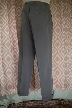 Gray trousers hanging in front of a patterned curtain