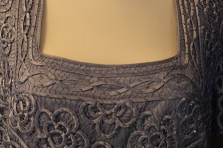 Close-up of an ornate dark lace neckline with a beige inset panel