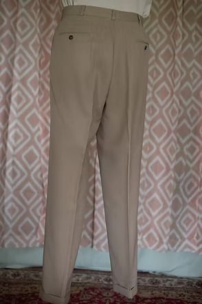 Beige pants hanging against a patterned wall, with shoes visible at the bottom.