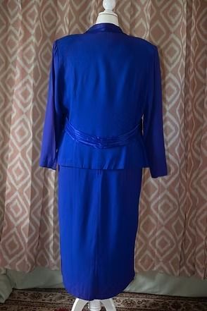 Blue sleeveless dress on a mannequin against a patterned curtain.