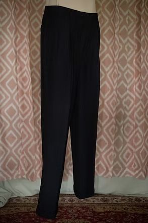 Black dress pants hanging against a patterned curtain.