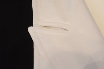 Black-and-white tailored blazer on a mannequin, with contrasting white lapels and cuffs and three buttons.