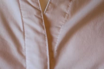 Close-up of a light pink zippered jacket with a vertical seam.
