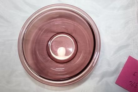 Top-down view of a pink glass bowl on a white surface with a small pink note nearby.