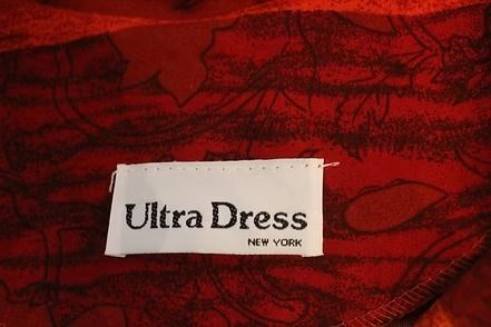 Red long dress on a mannequin against a brown curtain backdrop.