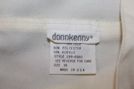 Cream-colored pants laid flat on a leafy patterned background.
