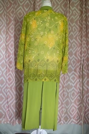 Bright green floral blouse and matching pants displayed on a mannequin against a patterned backdrop