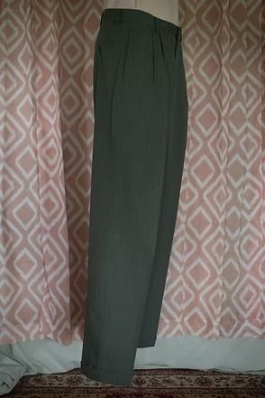 Dark green trousers hanging in front of a pink patterned curtain.