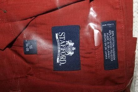 Close-up of a red Stafford garment label with black tags on textured fabric.