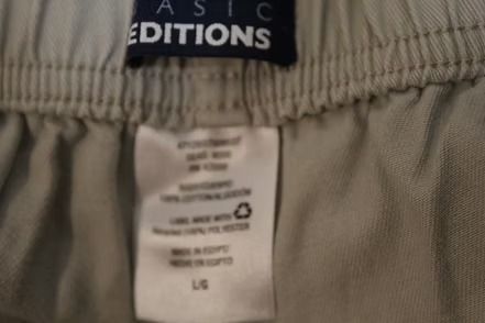 Light gray knee-length shorts hanging against a beige wall.