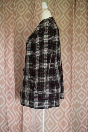Plaid black, white, and red blazer on a mannequin against a pink patterned backdrop