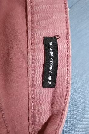 Pink pants laid flat on a patterned surface with green leaves and lemons.