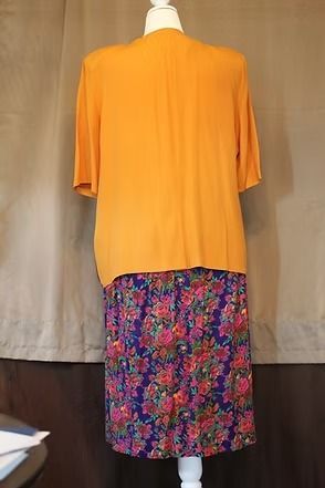 Orange jacket and floral skirt on a mannequin against a plain backdrop