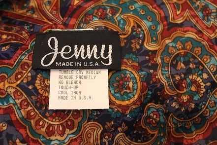 Close-up of a Jenny Made in USA clothing label on a colorful paisley fabric.