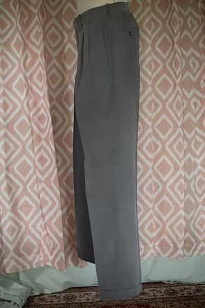 Gray trousers hanging in front of a patterned curtain