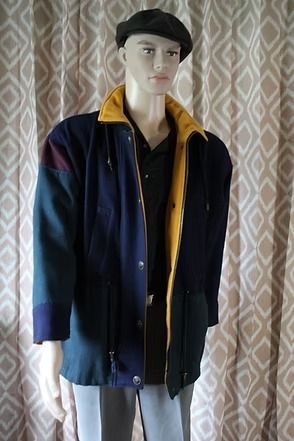 Mannequin wearing a navy jacket with yellow lining, black cap, and black shirt in front of curtains