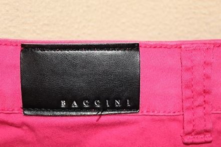 Bright pink shorts clipped to a hanger against a beige background.