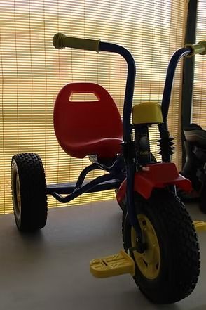 Red and blue child’s tricycle with yellow handles and pedals on a windowsill