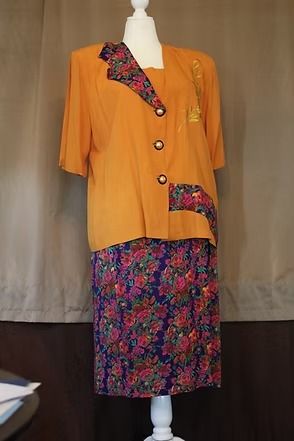 Orange jacket and floral skirt on a mannequin against a plain backdrop