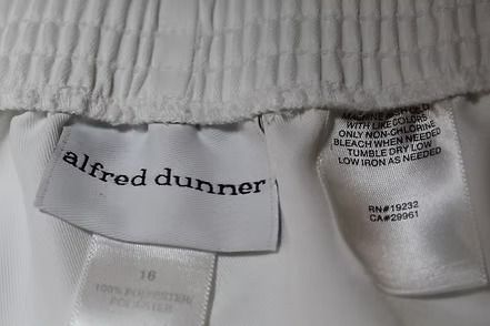 White pants hanging on a hanger against a plain background