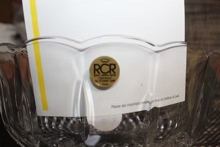 Clear glass bowl with scalloped edges and a gold sticker, on a textured placemat.