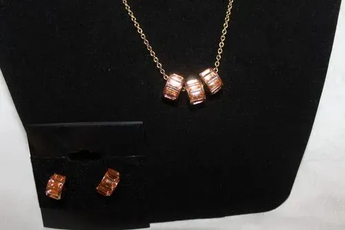 Gold necklace and matching earrings with rose-gold bead accents on a black display card.