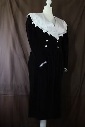 Black vintage dress with white lace collar and cuffs on a mannequin against a dark backdrop