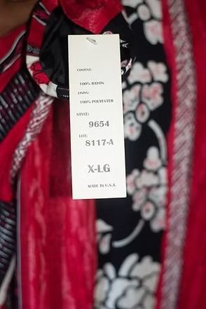 Red, black, and white patterned jacket on a mannequin against a patterned curtain backdrop
