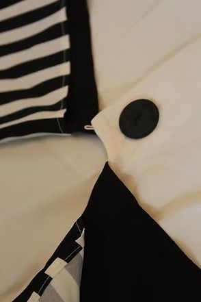 White short-sleeve blouse on mannequin with large black-striped collar and black buttons