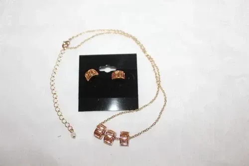 Gold necklace and matching earrings with rose-gold bead accents on a black display card.