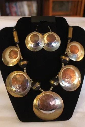Gold-and-silver oval jewelry set on a black display bust with matching necklace and earrings