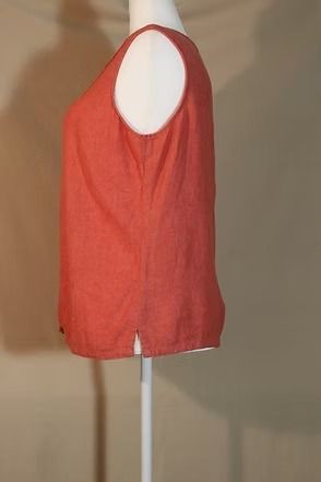 Coral sleeveless top on a mannequin, shown from the back against a beige wall.