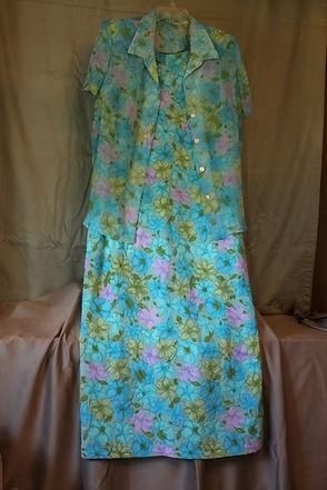 Floral blue-green button-up dress hanging against a tan backdrop