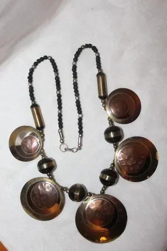 Gold-and-silver oval jewelry set on a black display bust with matching necklace and earrings