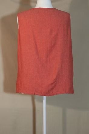 Coral sleeveless top on a mannequin, shown from the back against a beige wall.