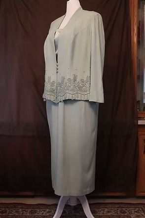 Light gray formal jacket and skirt outfit on a mannequin against a dark backdrop.
