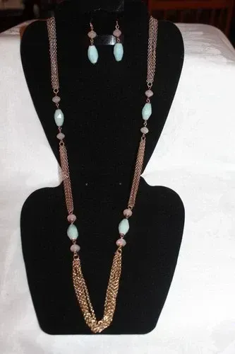 Gold and mint-green beaded necklace with matching earrings displayed on a black bust stand