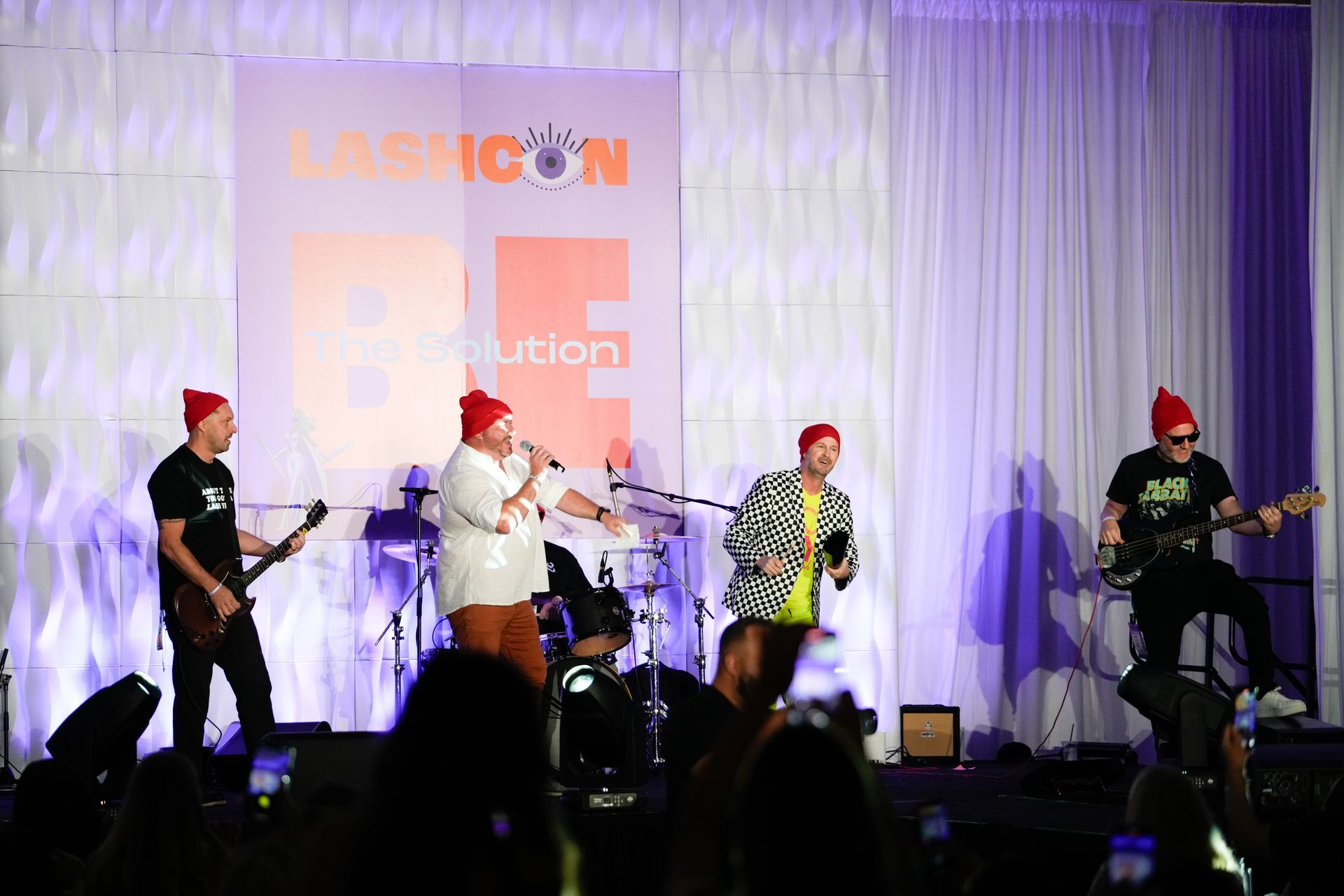 A group of people are playing instruments on a stage in front of a sign that says fashion