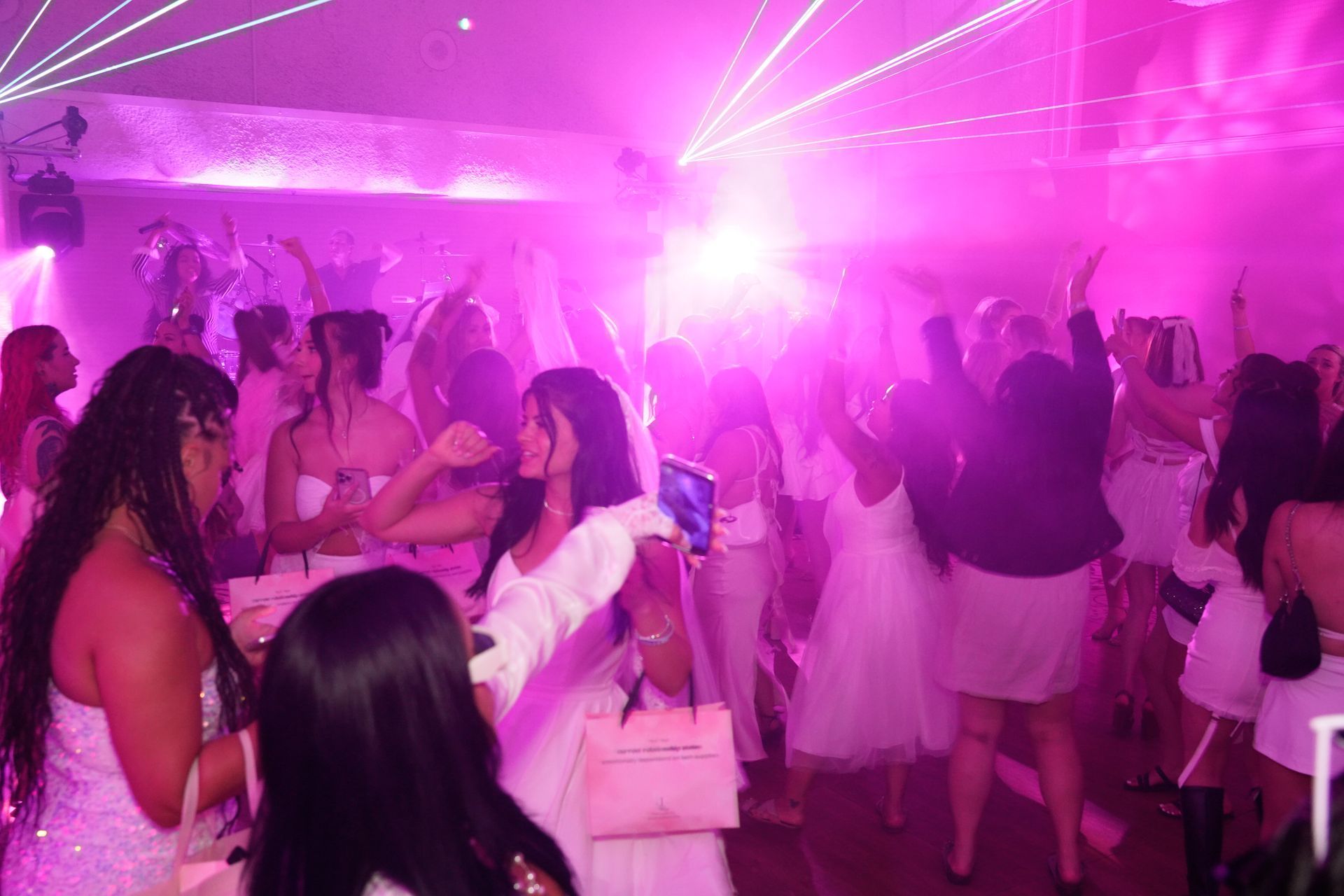 A group of women are dancing in a room with purple lights.