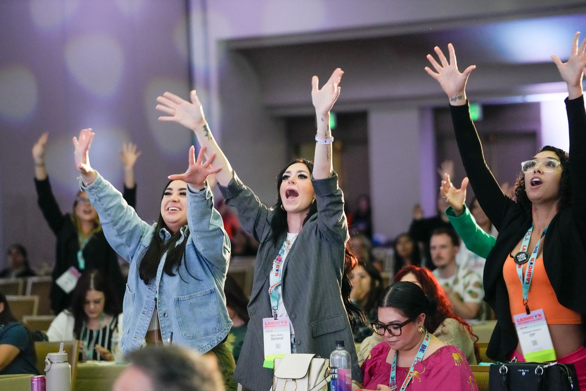 A group of women are sitting in a room with their arms in the air.