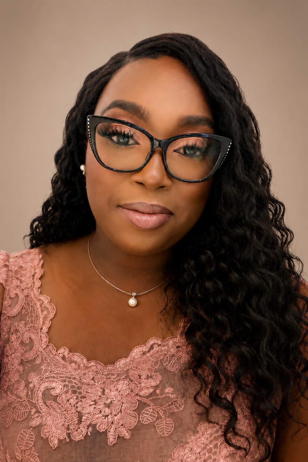 Portrait of a woman wearing black glasses and a pink lace top against a neutral background
