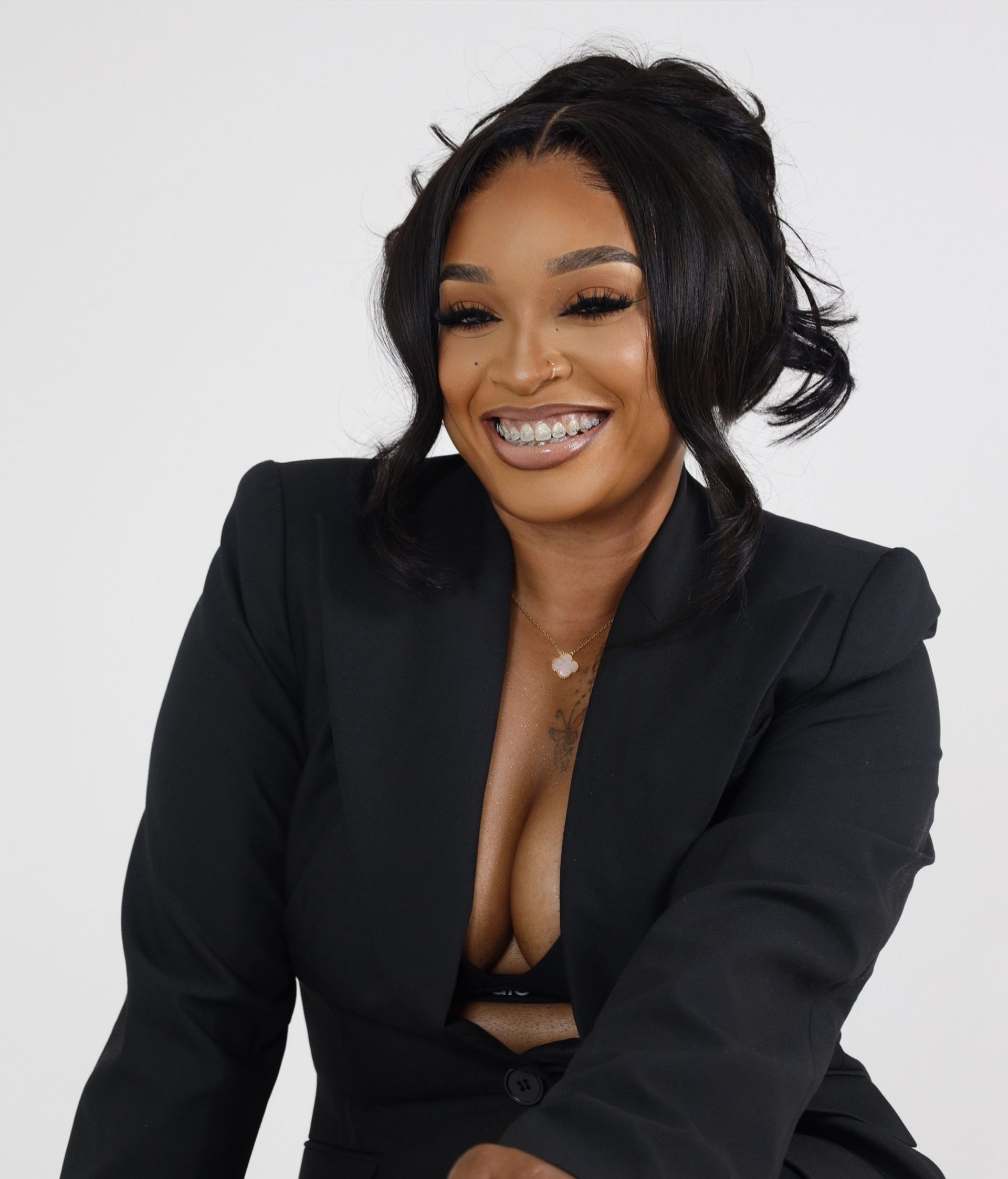 Smiling woman in a black blazer posing against a plain white background.