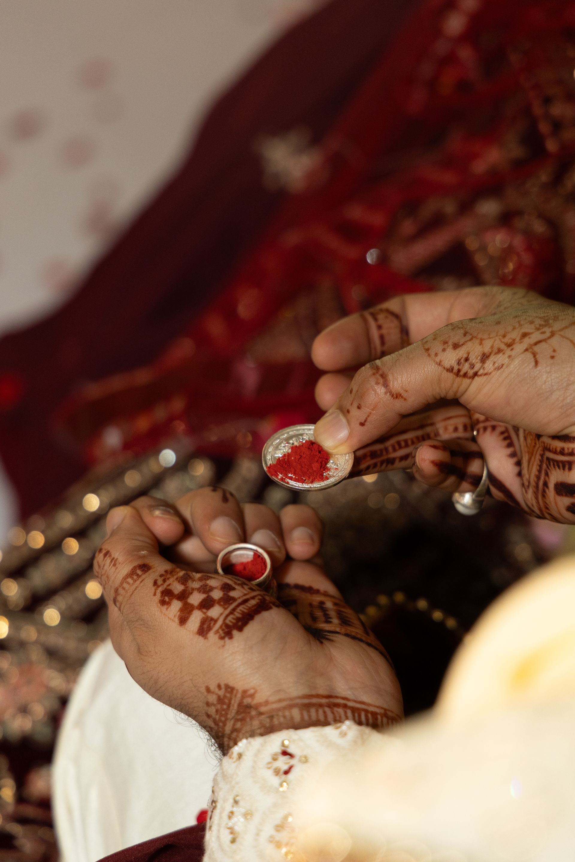 Handen versierd met henna wisselen rode ringen uit tijdens een traditionele ceremonie.