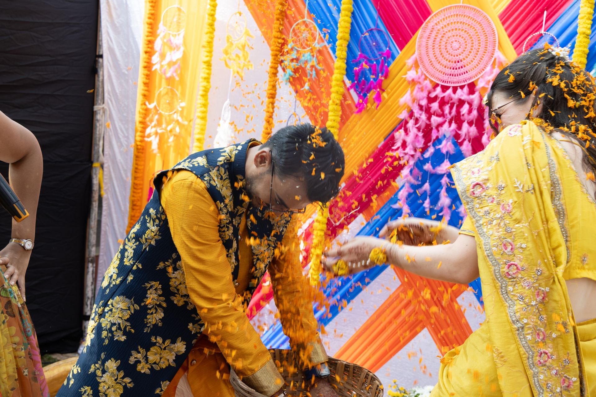 Mensen in kleurrijke traditionele kleding vieren feest met bloemblaadjes tijdens een feestelijk evenement.