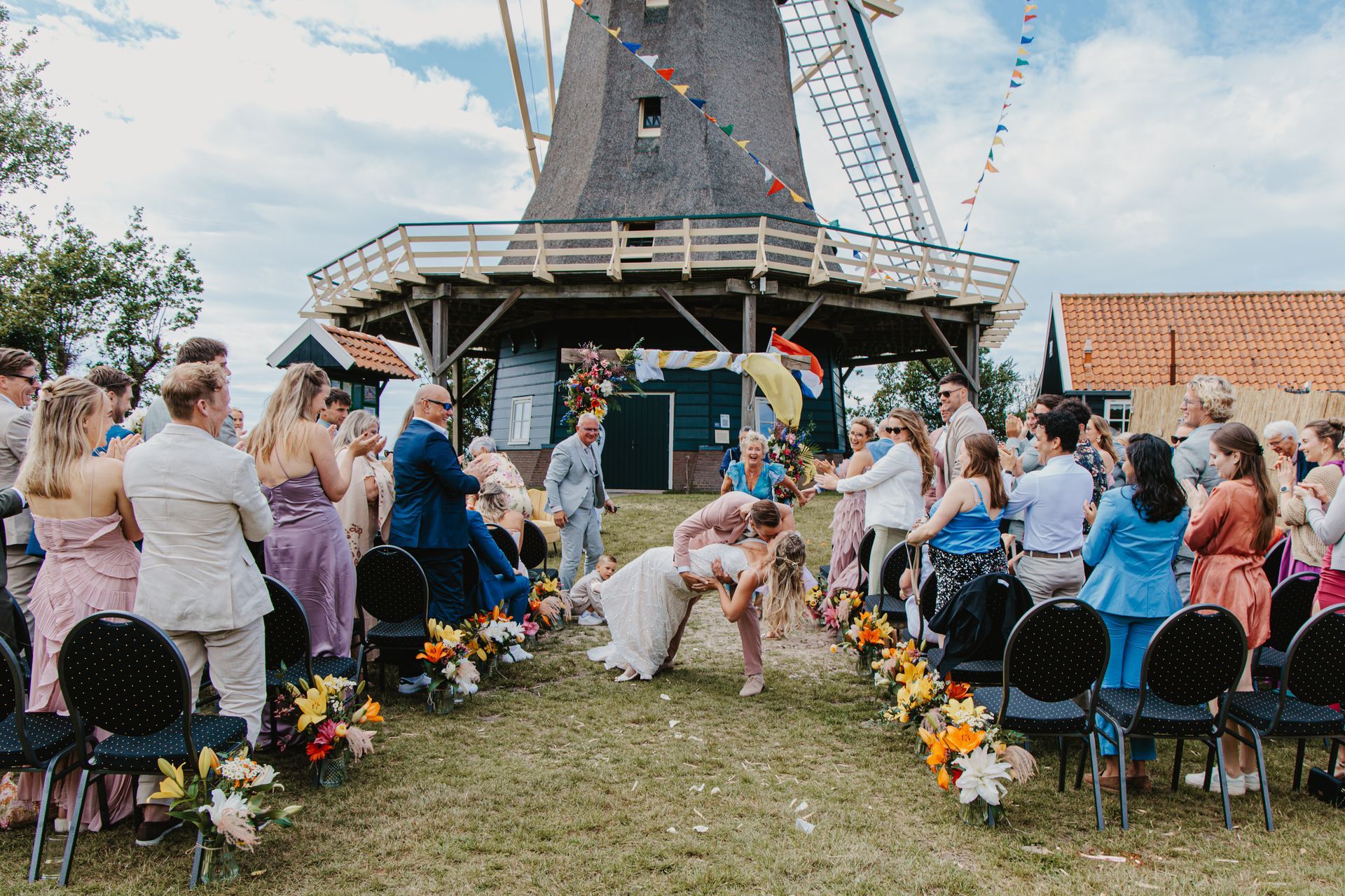 Close-up van trouwringen op een witte roos, omringd door donkere bessen en roze bloemblaadjes.