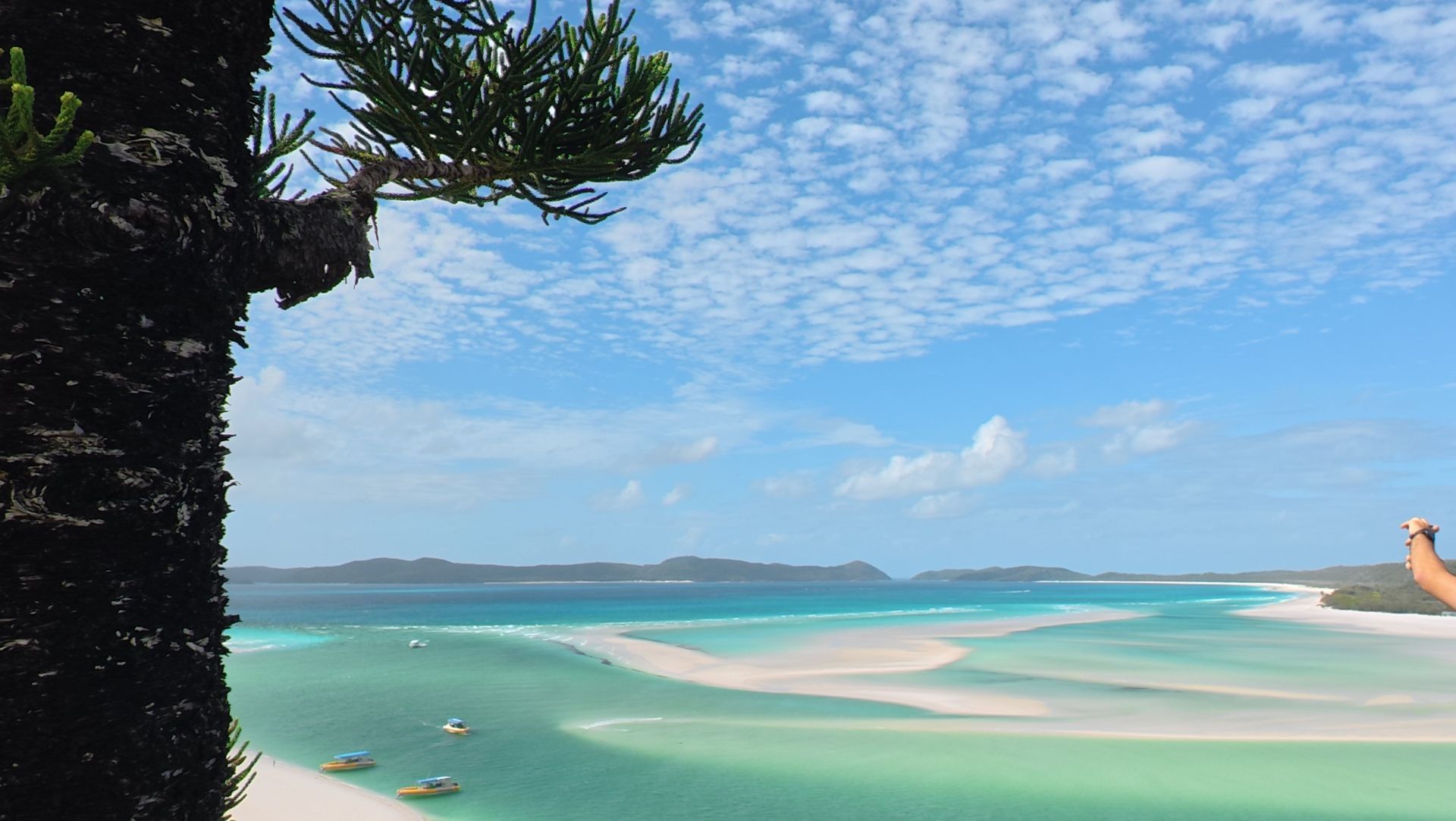 Tropisch strand met turquoise water, witte zandbanken en een blauwe hemel met hier en daar wat wolken.
