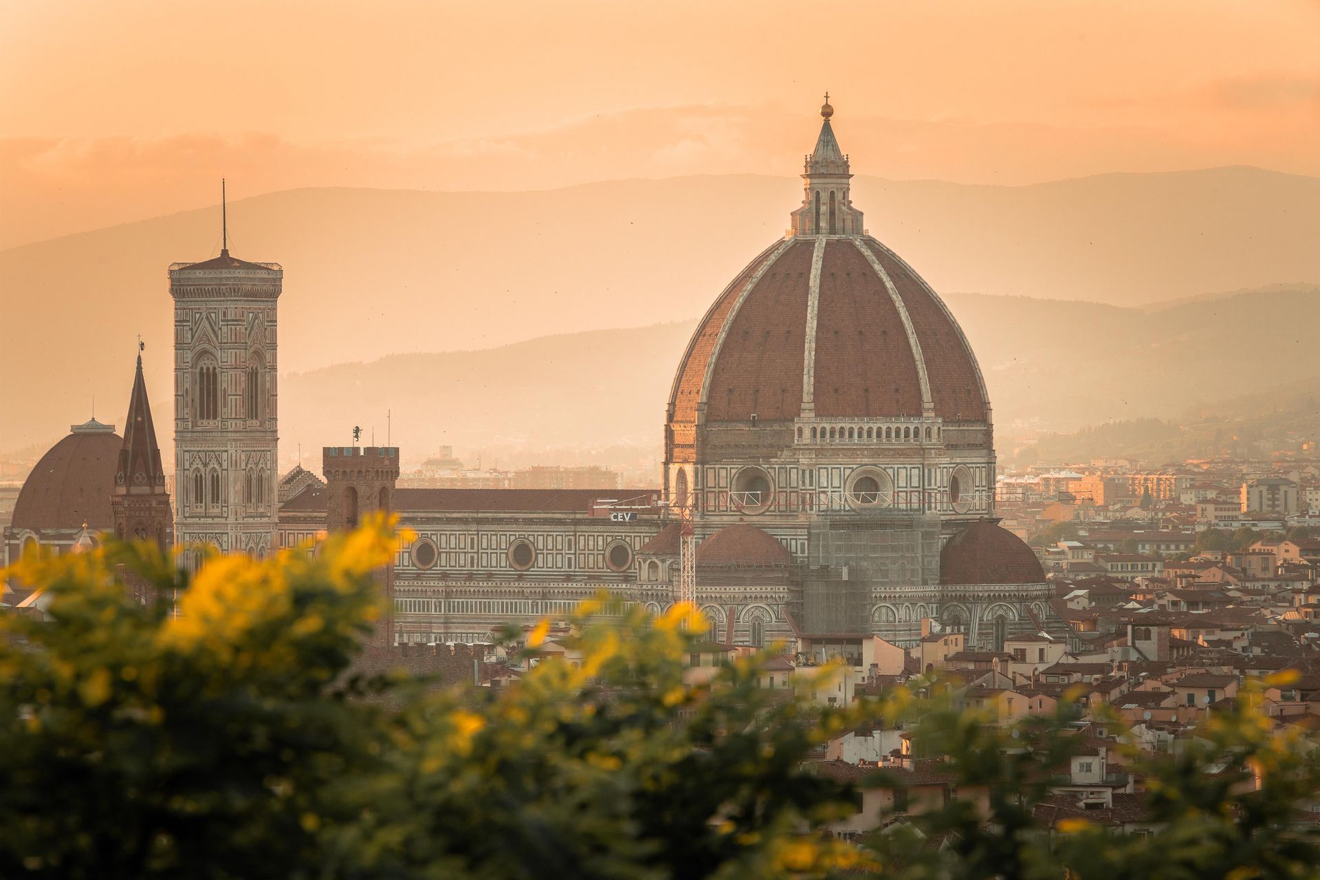 De skyline van Florence bij zonsopgang, met de koepel van de Duomo en de klokkentoren van Giotto boven de nevelige heuvels.