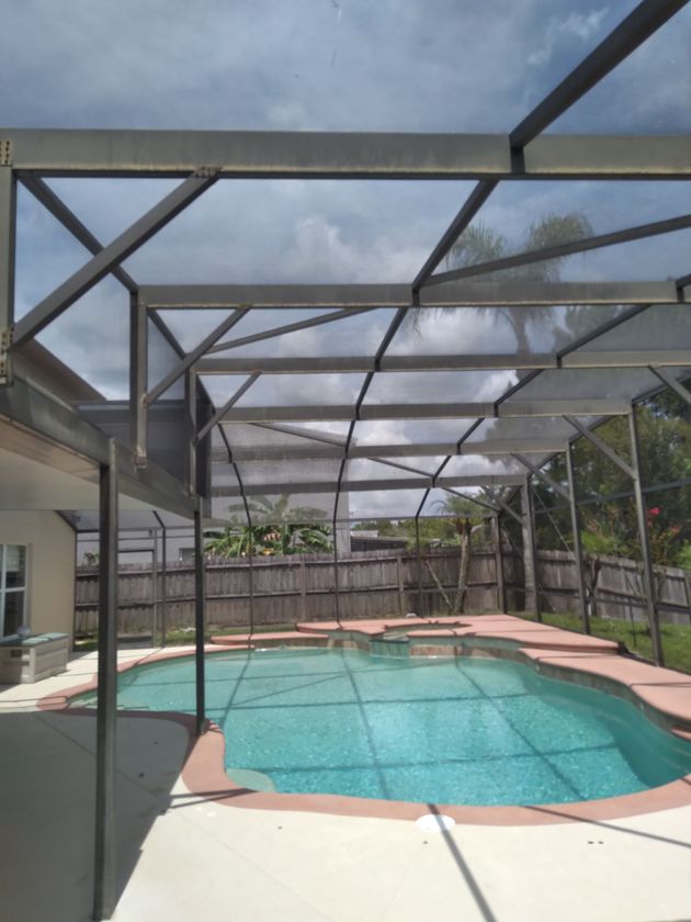 Sliding glass patio door with gray blinds beside a potted plant on a sunny porch