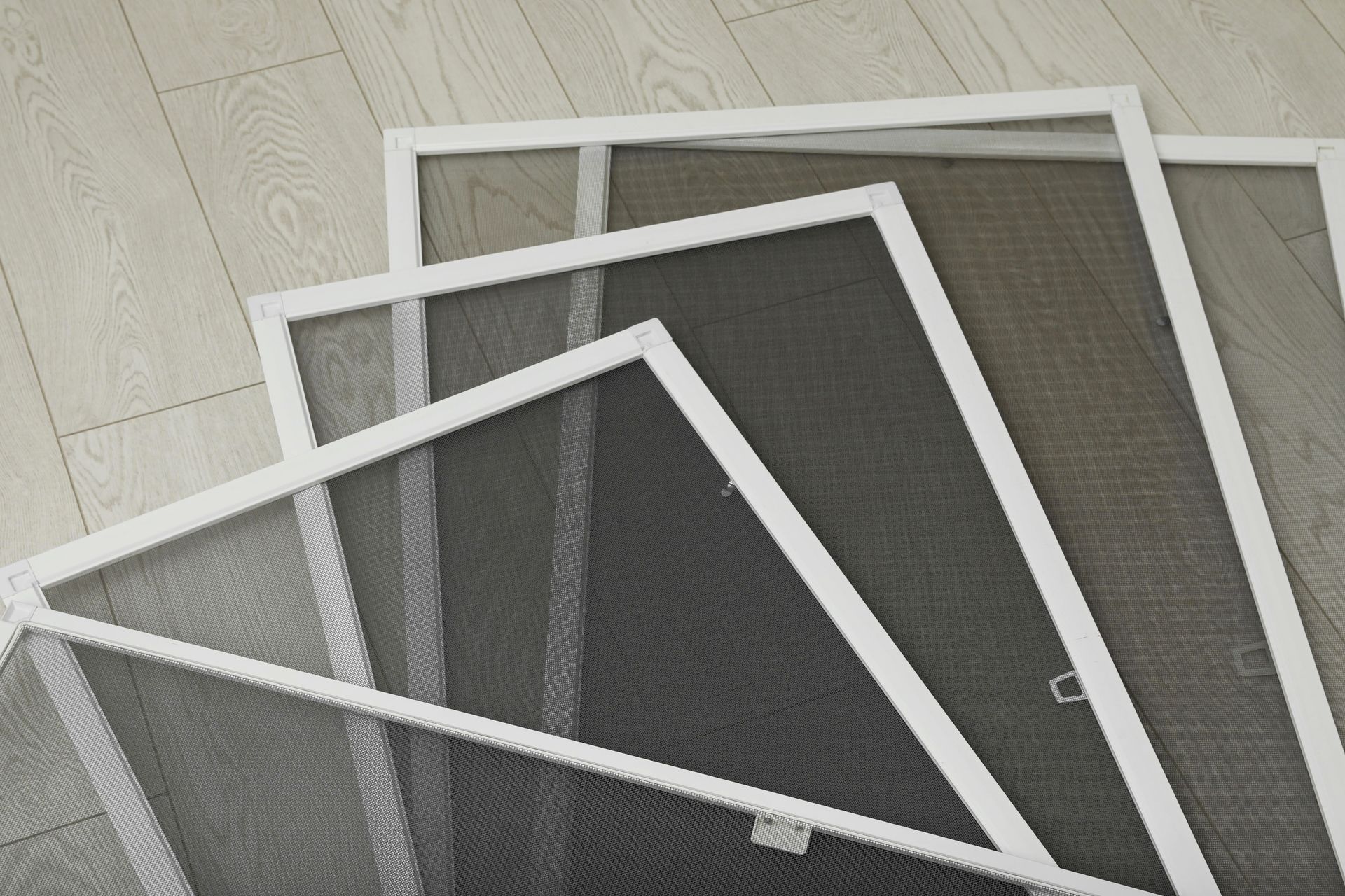 Stacked white-framed window screens on a light tiled floor
