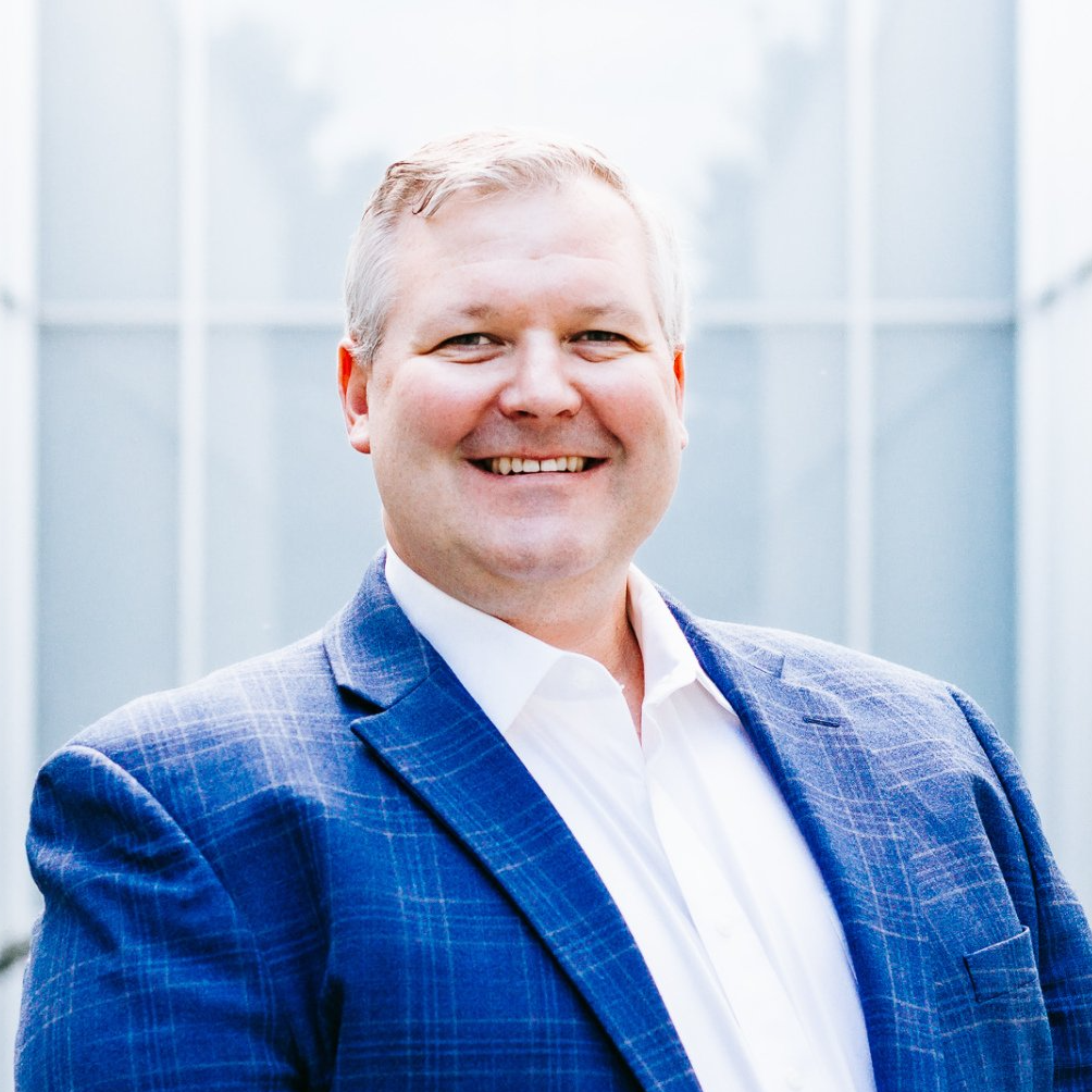 a man in a blue suit and white shirt is smiling for the camera .